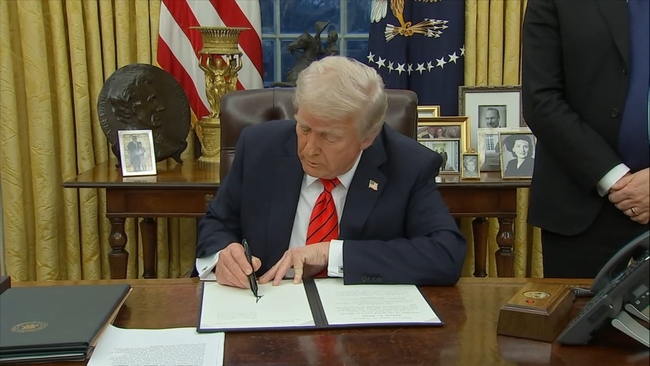 Trump signing documents in the Oval Office, issuing a presidential pardon.